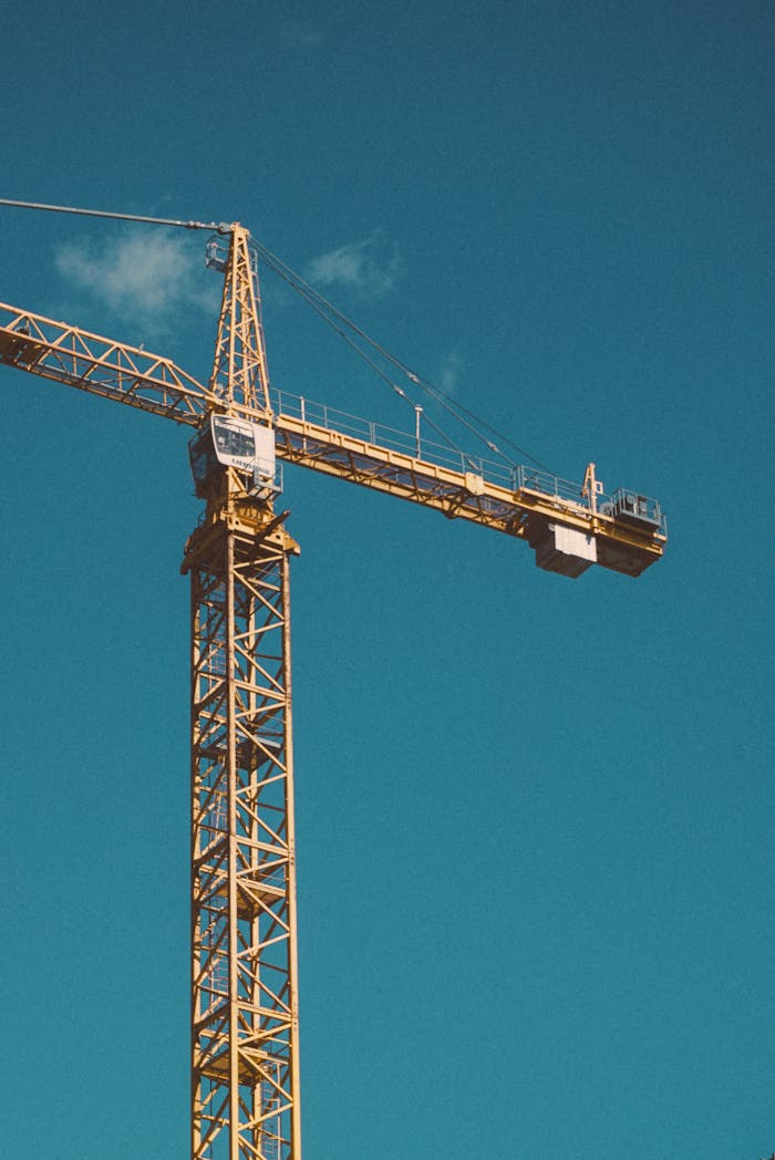 our-experience A large construction crane stands tall against a bright blue sky.