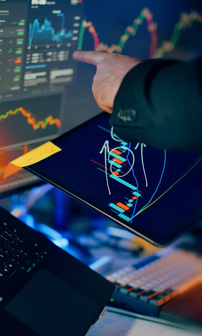 gallery-6 A business professional examines financial charts on a tablet and monitor for investment strategy.