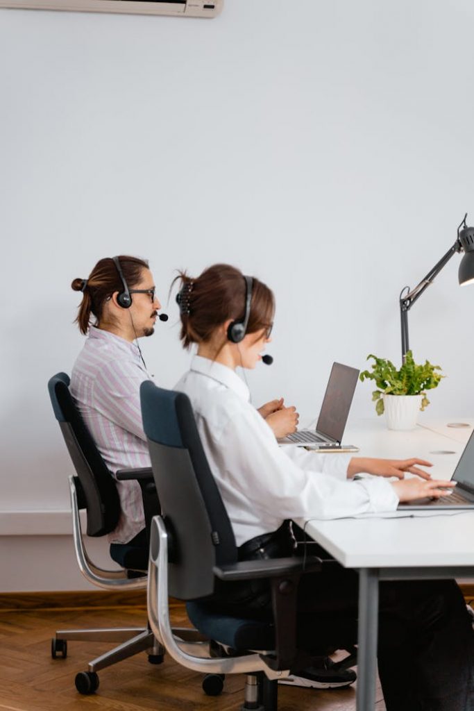 Mastering the First Impression: Your intriguing post title goes here Two call center employees working with laptops and headsets in an office.