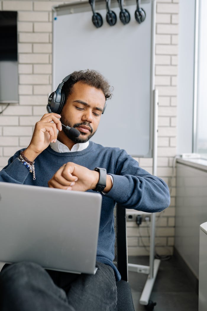 contact-img Confident man with headset multitasking in a modern office setting. Ideal for business and technology themes.