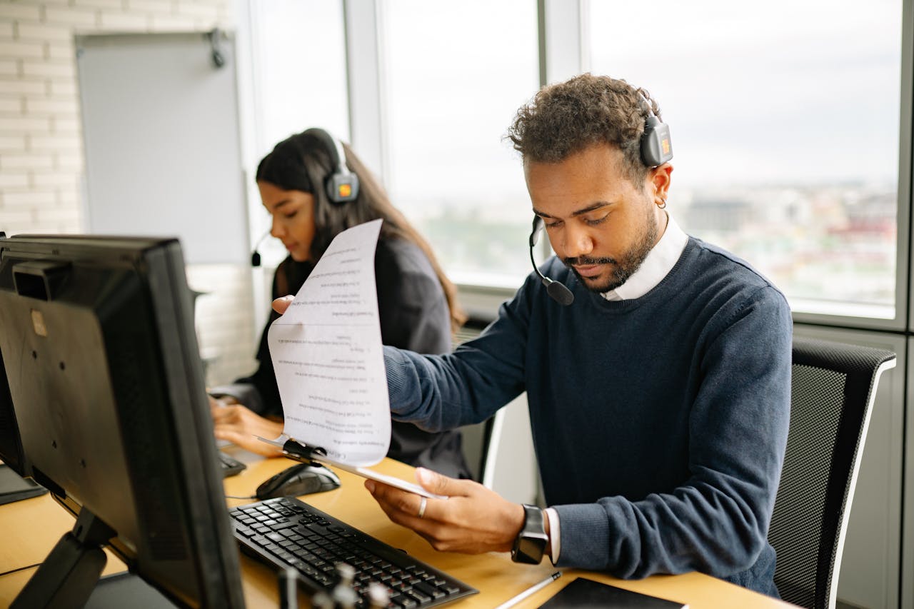 about-01 Call center agents with headsets working in a modern office setting, reviewing documents.